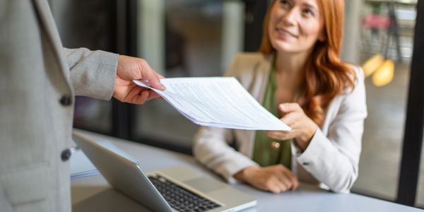 A woman receiving a document from a man in an office setting.