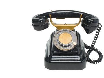 A vintage black rotary dial telephone.