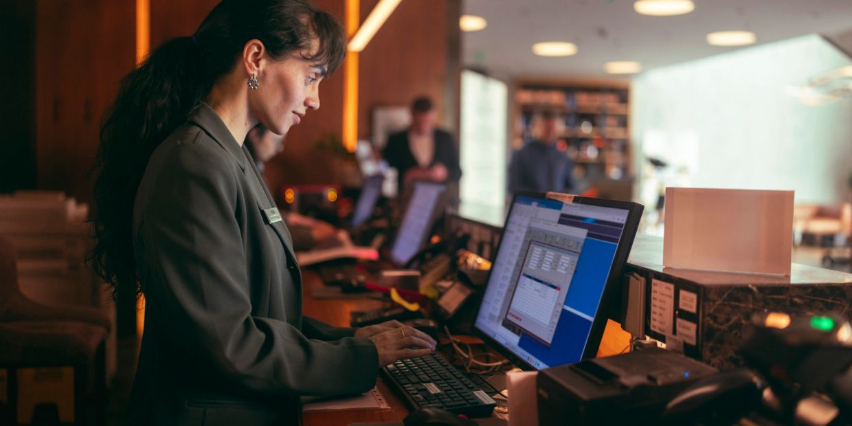 Recepcionista trabajando en el computador en un hotel.
