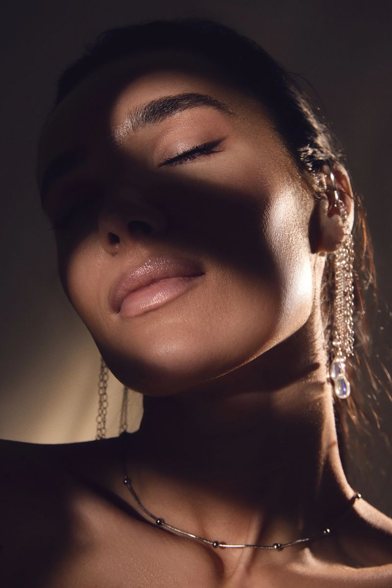 Close up beauty portrait of woman with closed eyes and glowing skin in soft light. Concept of skincare advertising, wellness industry, cosmetic treatment and self care product promotion.