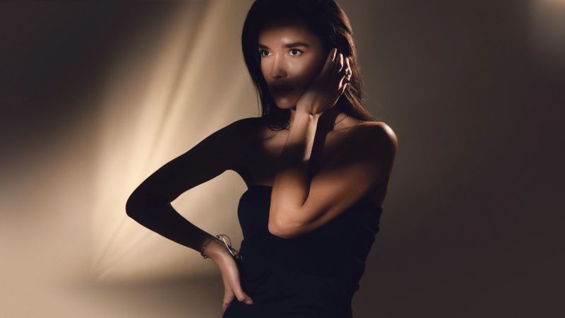 Fashion portrait of elegant woman posing with hand on face in studio lighting. Concept of product showcase, ecommerce visuals, fashion retail and accessory marketing content.
