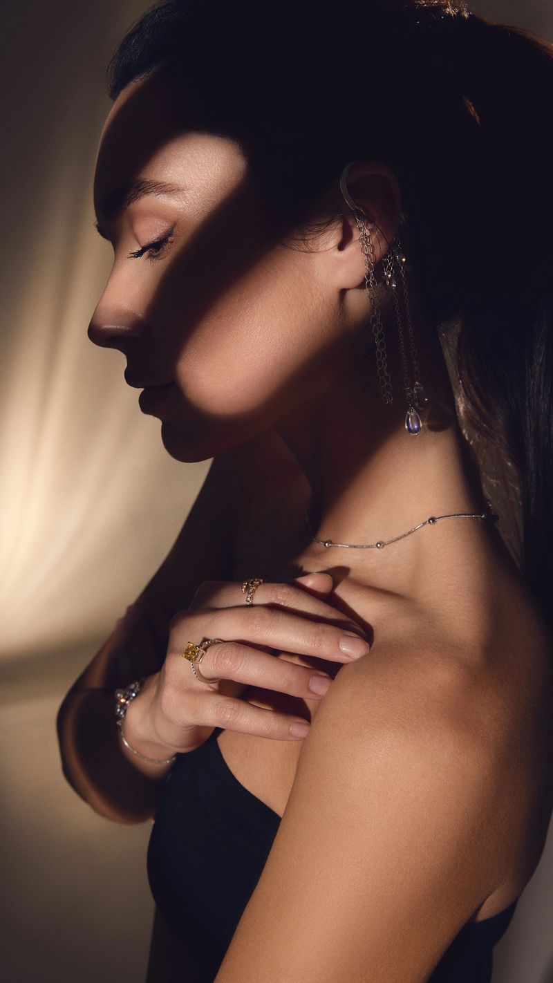 Side profile of elegant woman wearing jewelry in warm studio light with shadows. Concept of fashion branding, luxury accessories promotion, beauty industry visuals and premium advertising.