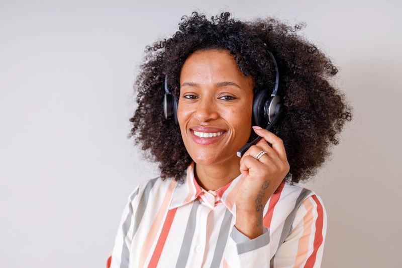Smiling customer service representative working from home with headset, providing online support in a call center