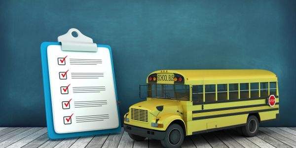 Model of a school bus and a checklist on a clipboard.
