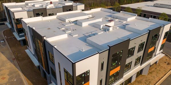 Aerial view of industrial building roofs with HVAC units and a nearby road.
