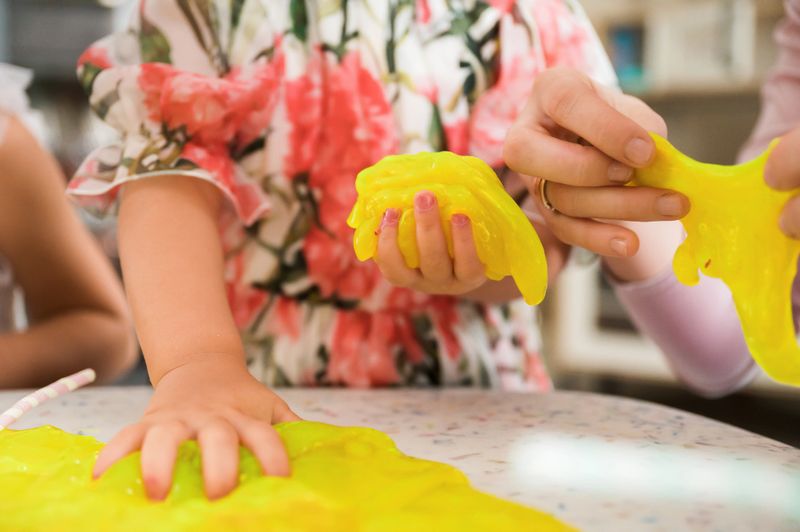 Children playing with bright stretchy slime exploring sensory textures and creative play during fun indoor activity supporting imagination and tactile learning development
