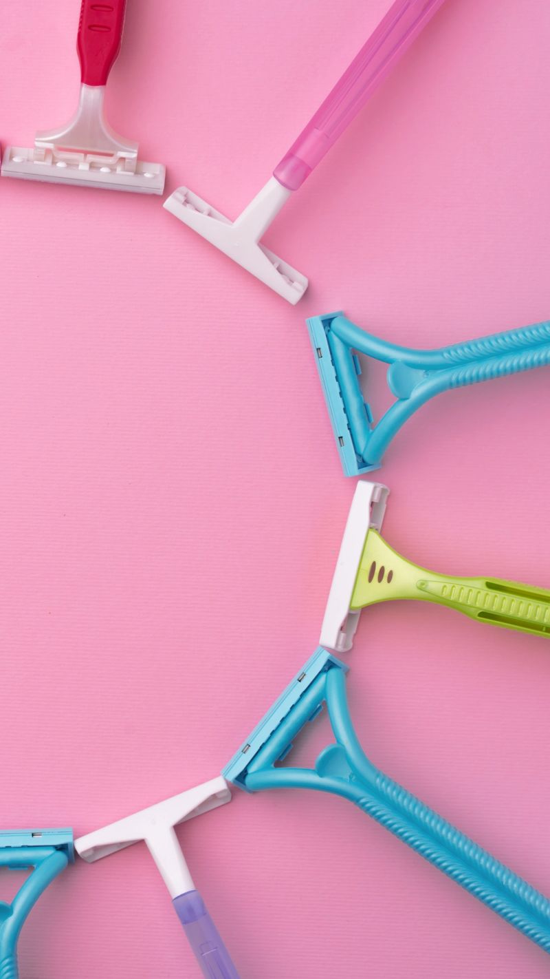 Colored razors arranged in a ring on a pink surface, showcasing various handles and blades.