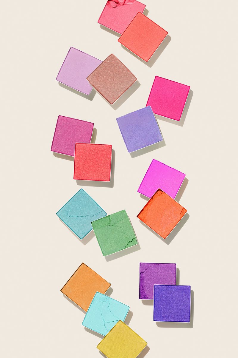 Cosmetic beauty product multicolor eyeshadows for makeup on light beige background, copyspace, color pallete swatches powder eyes, top view decorative cosmetics beauty product, shiny matte eye shadow