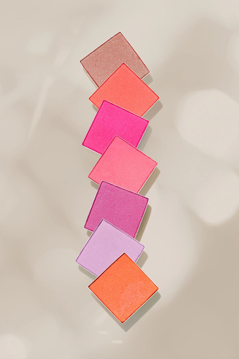 Cosmetic beauty product red pink eyeshadows for makeup on light pink background, copy space, color pallete swatches powder eyes, top view, decorative cosmetics beauty product, shiny matte eye shadow