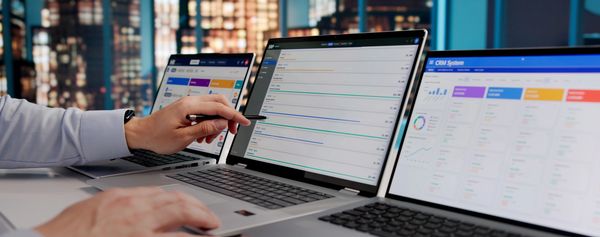 Person using multiple laptops with data on screens.