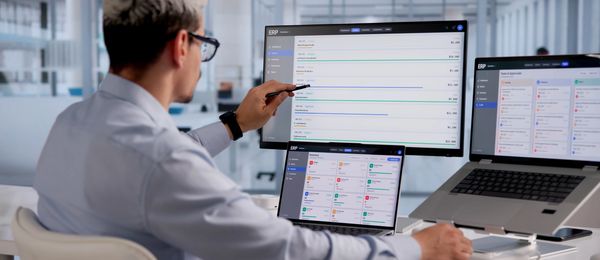 Man analyzing data on multiple screens in a modern office.