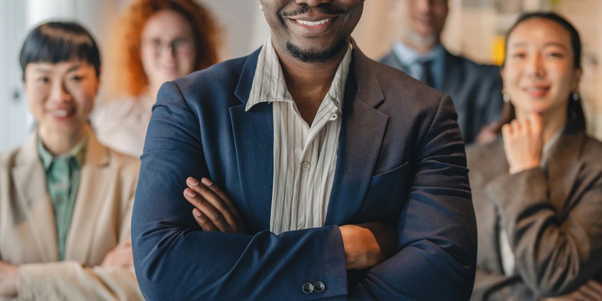 Confident professional leading a diverse team with smiles and crossed arms.