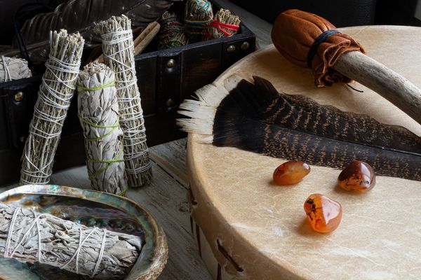 Smudge sticks, feathers, and amber stones on a drum.