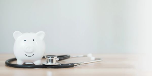 White piggy bank with a stethoscope on a wooden surface.