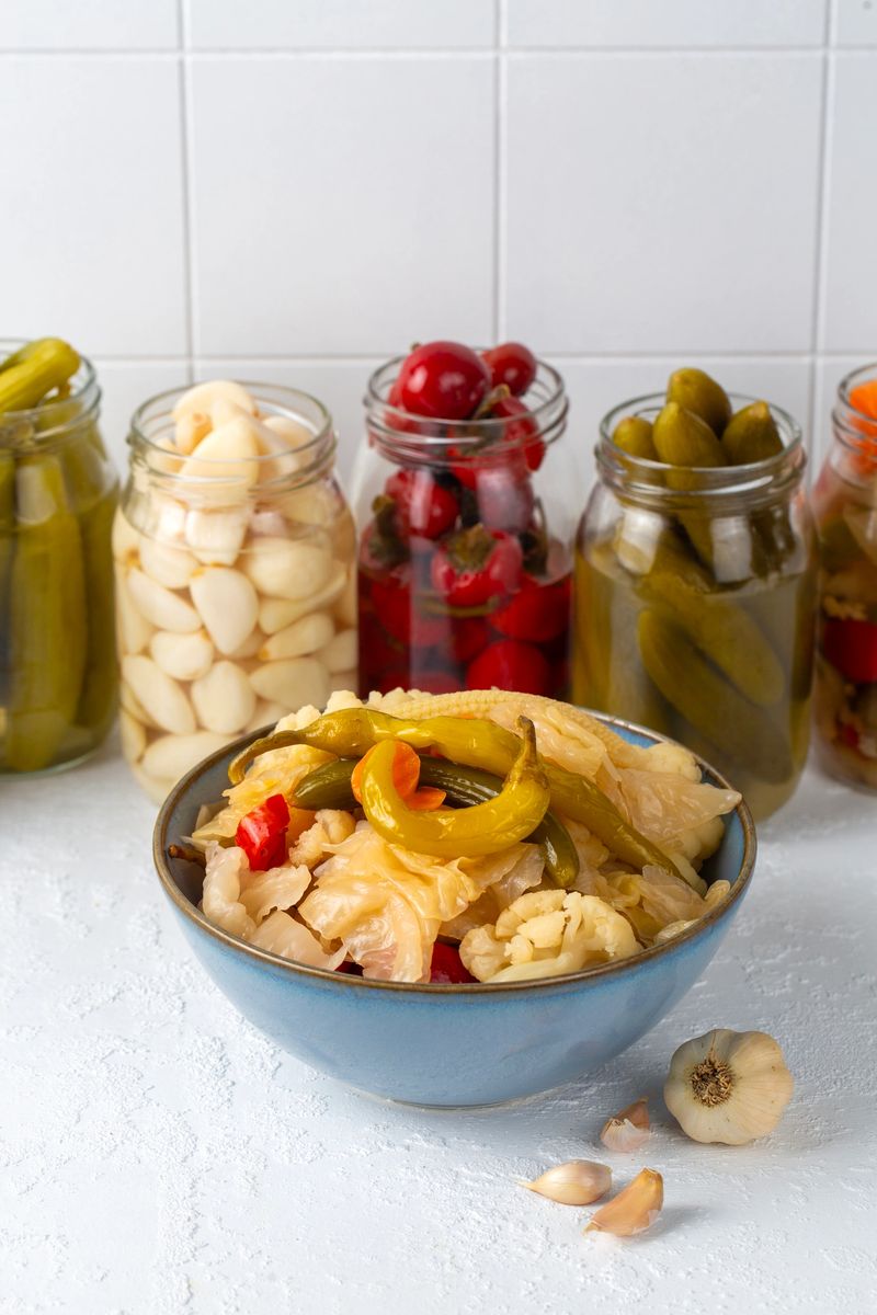 Assorted Homemade Pickled Vegetables in Glass Jars and a Blue Bowl