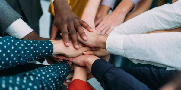Diverse group stacking hands in unity and teamwork.