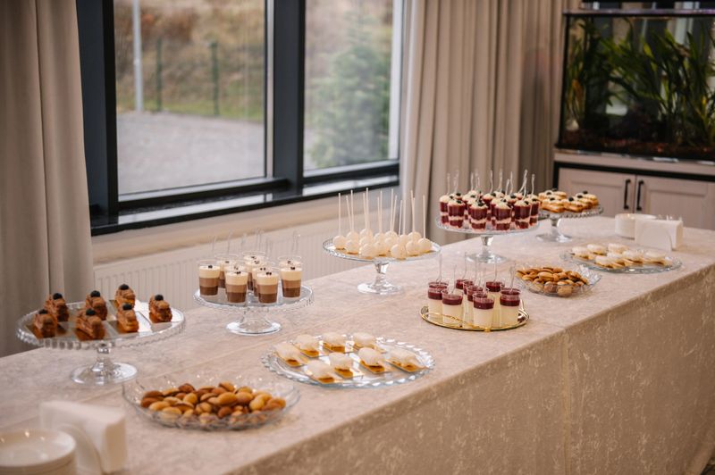 Elegant banquet table featuring a variety of gourmet catering desserts: mousse cups, eclairs, cakesicles, and cake pops. Beautifully arranged for a luxury wedding or festive event reception.