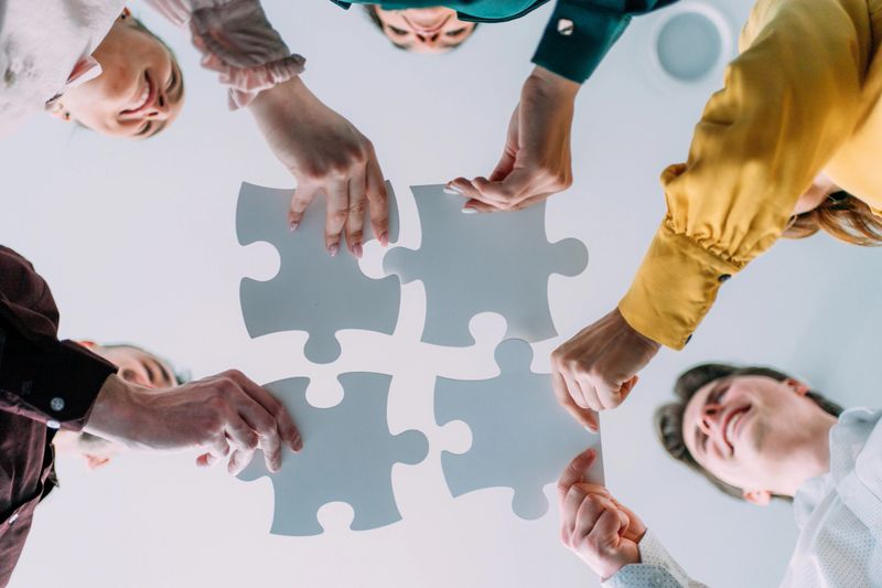 Low angle view of group of businesspeople connecting puzzle pieces in the office.