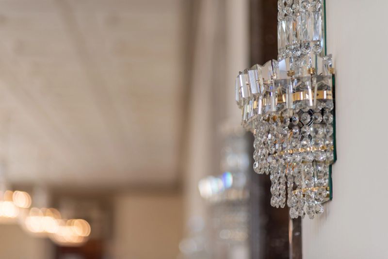 Close-up of a crystal wall sconce chandelier on a modern interior wall with soft bokeh lights and shallow depth of field, elegant hotel or home decor background.