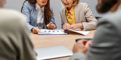 Two women discussing documents at a meeting.