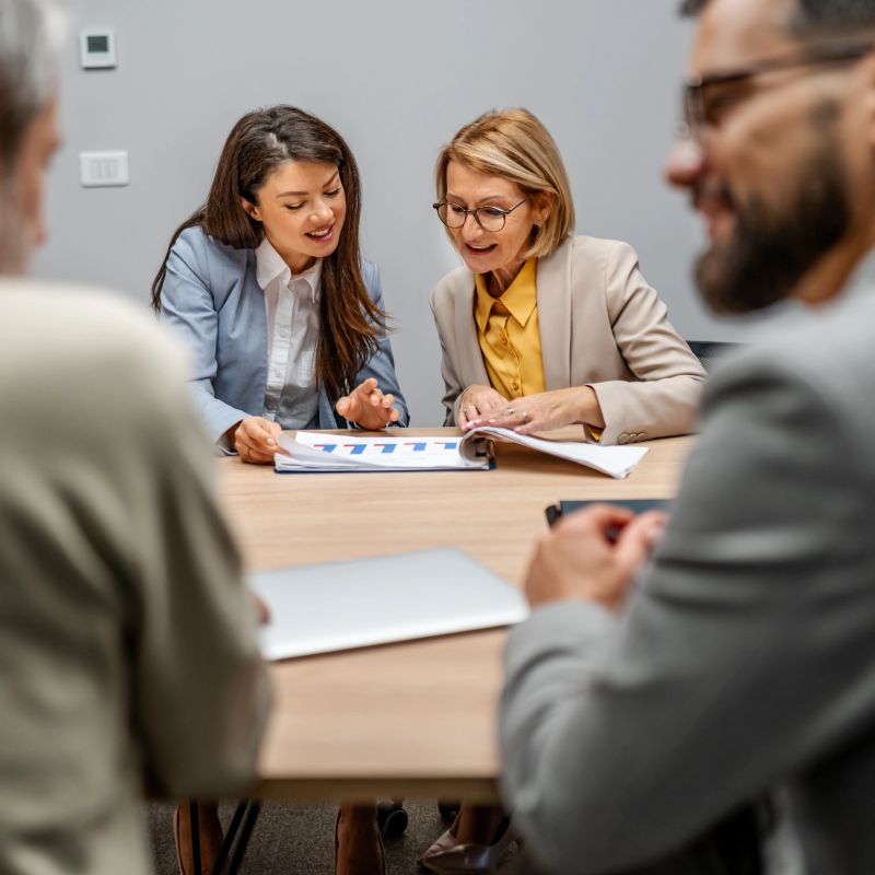 Businesswomen discussing financial charts and reports in a modern office, collaborating on strategy and planning
