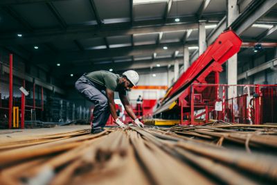 Worker inspecting rods in an industrial warehouse.