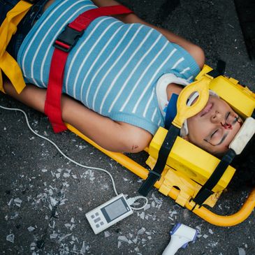 Child secured on a stretcher with a neck brace and monitoring device.