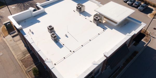 Aerial view of a flat white commercial building roof with HVAC units.