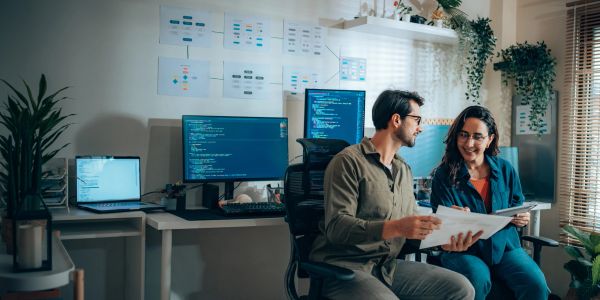 Two developers discussing code in an office.