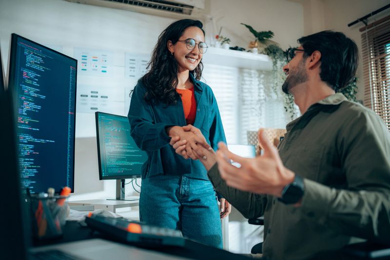 Hispanic software developers shaking hands after successful project