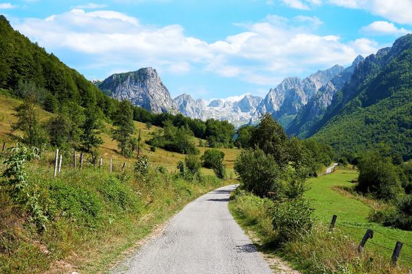 A winding road through green hills with mountains in the background.