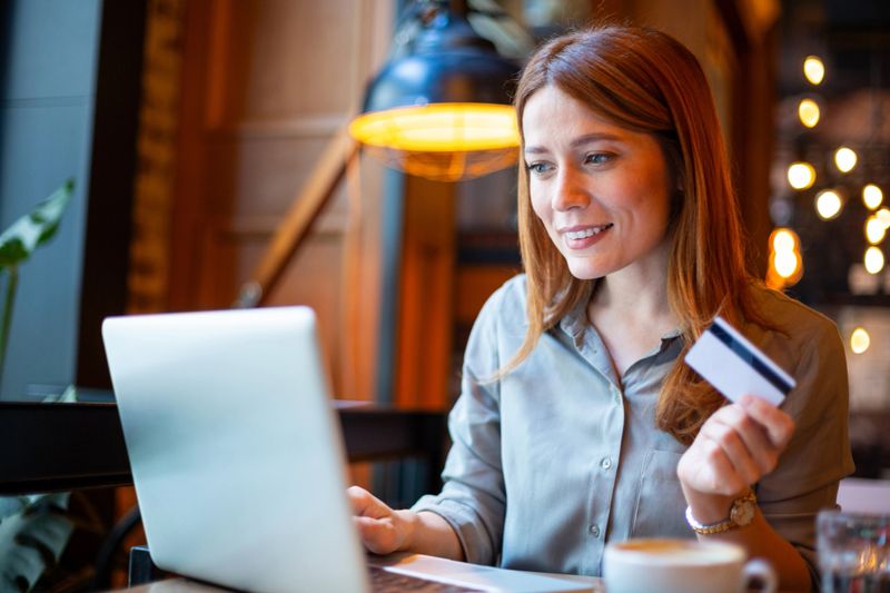 Woman smiling, making online purchase with credit card and laptop