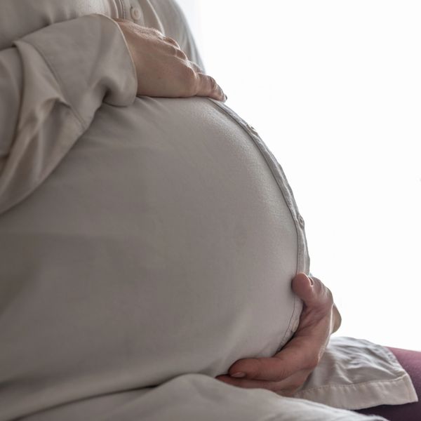Close-up of a pregnant belly with hands gently resting on it.