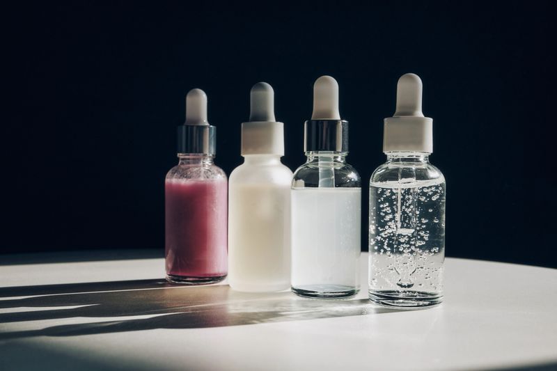 Four glass bottles with pipettes containing different cosmetic serums on a table