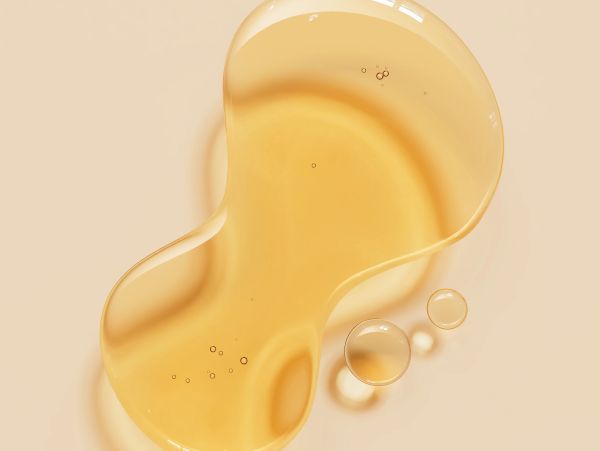Close-up of a golden liquid drop with bubbles.