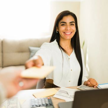 Woman happily handing over an envelope.