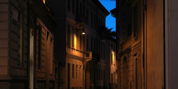 Quiet narrow street illuminated by warm streetlights at dusk.