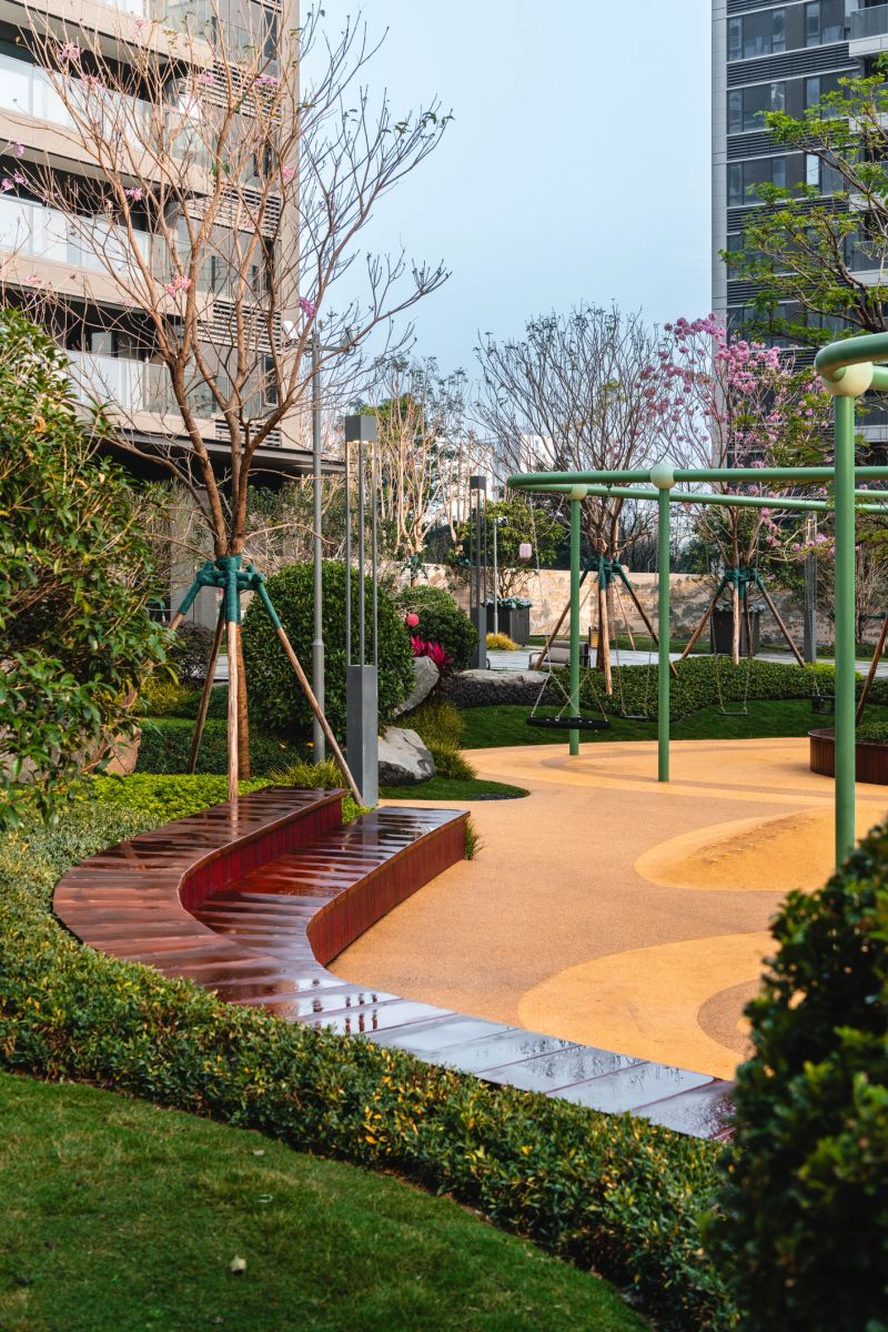 Modern urban playground with a curved wooden bench and green swing set. Scene details: contemporary, clean, serene