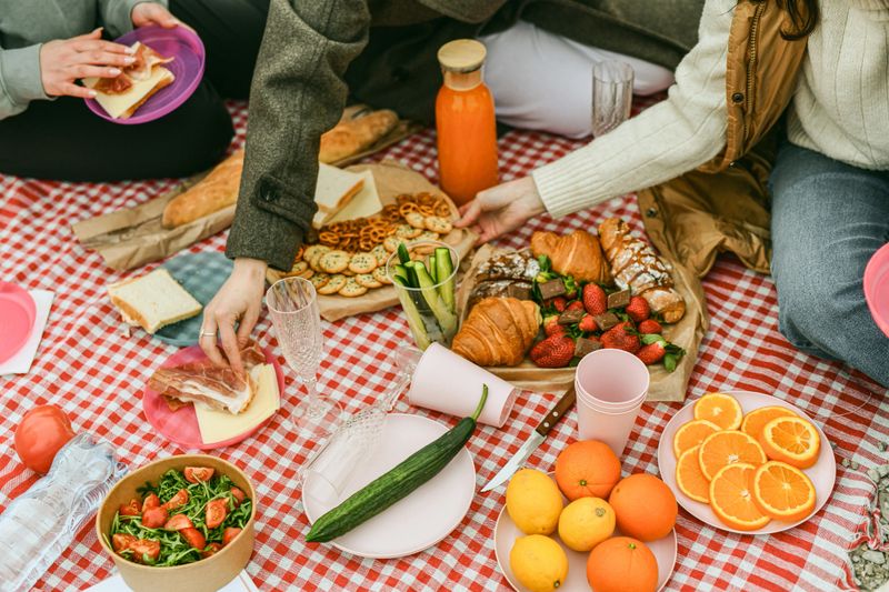 Overhead shot of a picnic setup highlighting colorful fruits and snacks neatly arranged on a blanket, perfect for showcasing outdoor leisure and healthy lifestyle concepts.