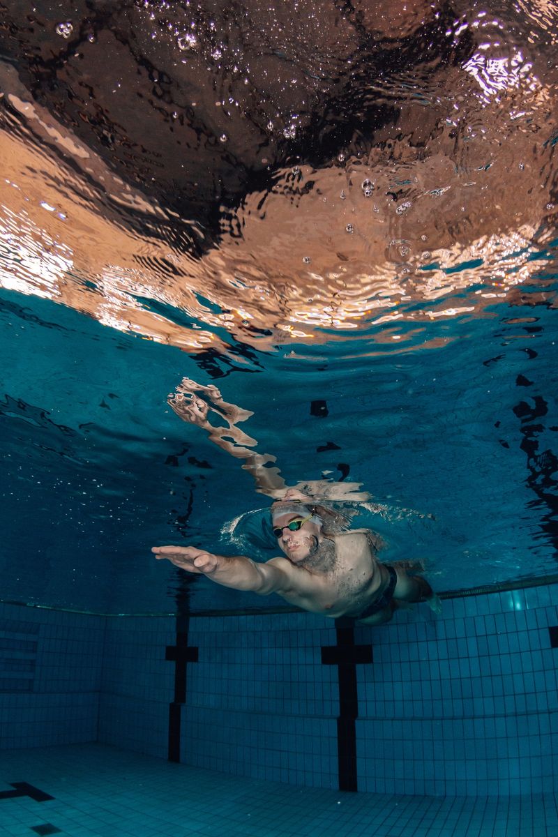 Man swimming underwater in a clear pool, actively training and building endurance with proper form and focus