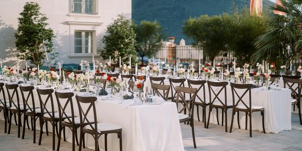 Elegant outdoor dining setup with white tablecloths and floral centerpieces.