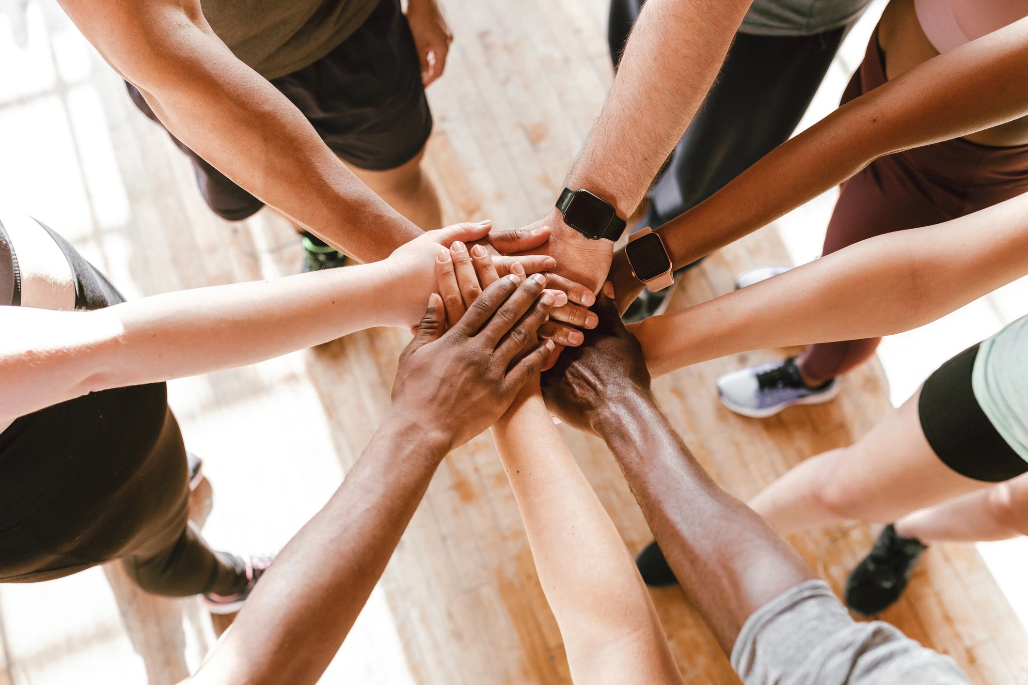 Aerial view of 7 or more people with their hands in the center.