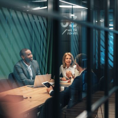 Three professionals engaged in a meeting inside a modern office room.