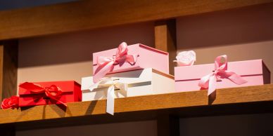 Stack of gift boxes with ribbons on a wooden shelf.