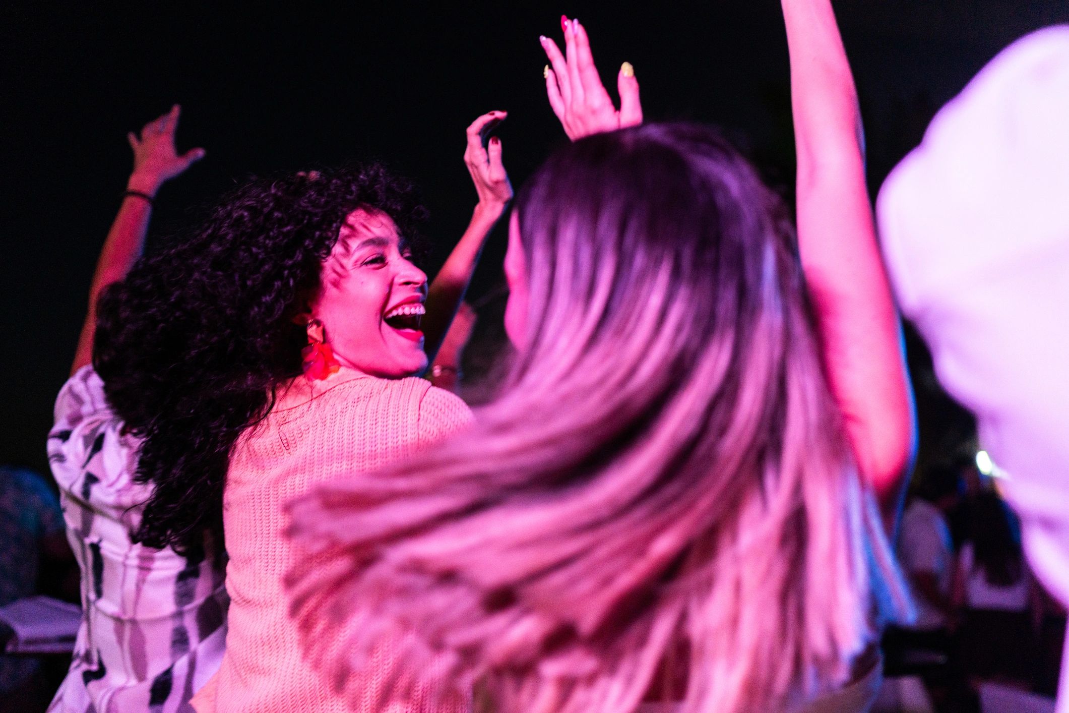 Friends dancing joyfully at a vibrant night party with colorful lights.