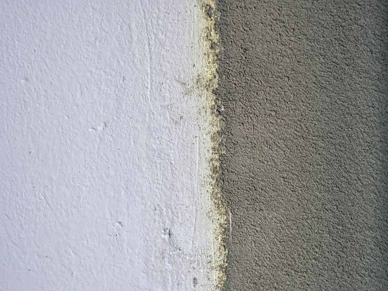 Close-Up of Wall Surface Showing Contrast Between Smooth White Paint and Rough Grey Cement Render — Renovation Before and After, Plastering, Construction and Wall Repair Concept