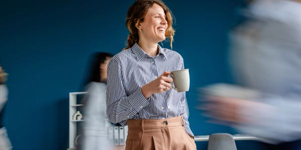 Smiling woman holding a coffee mug in an office.