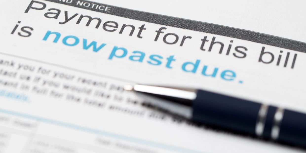 Close-up of a past due bill notice with a pen.