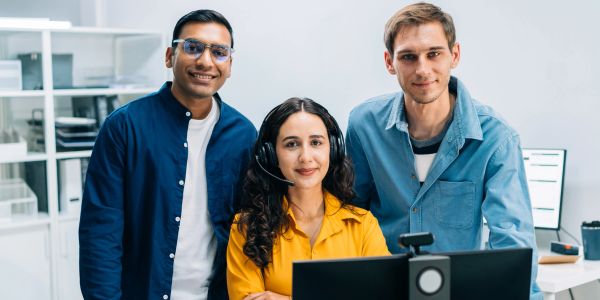 Tres jóvenes profesionales sonrientes en una oficina.
