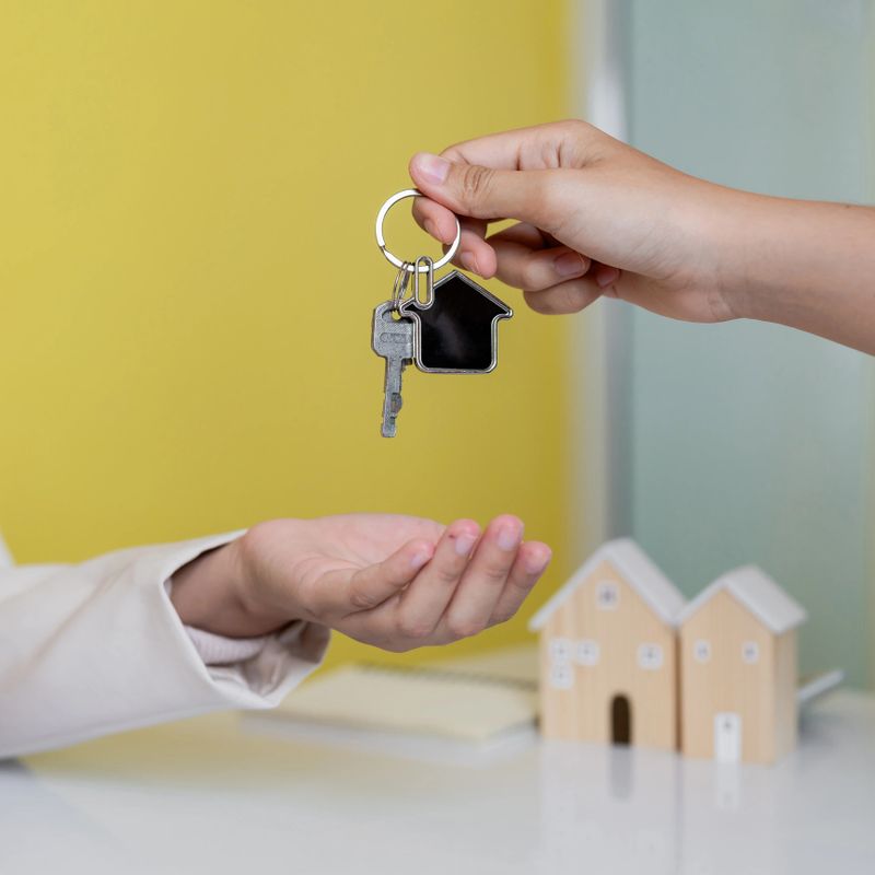 Real estate agent handing house keys with house shaped keychain to client. Property purchase and closing deal